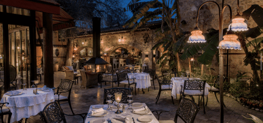 Restaurant extérieur au crépuscule, éclairé par des lumières chaudes.